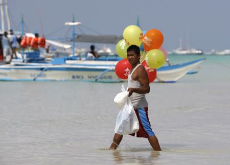 A man carries balloons and supplies to a boat moored off the beach in Boracay, one of the world's most famous beach resort, south of Manila February 3, 2008. REUTERS/Darren Whiteside/Files