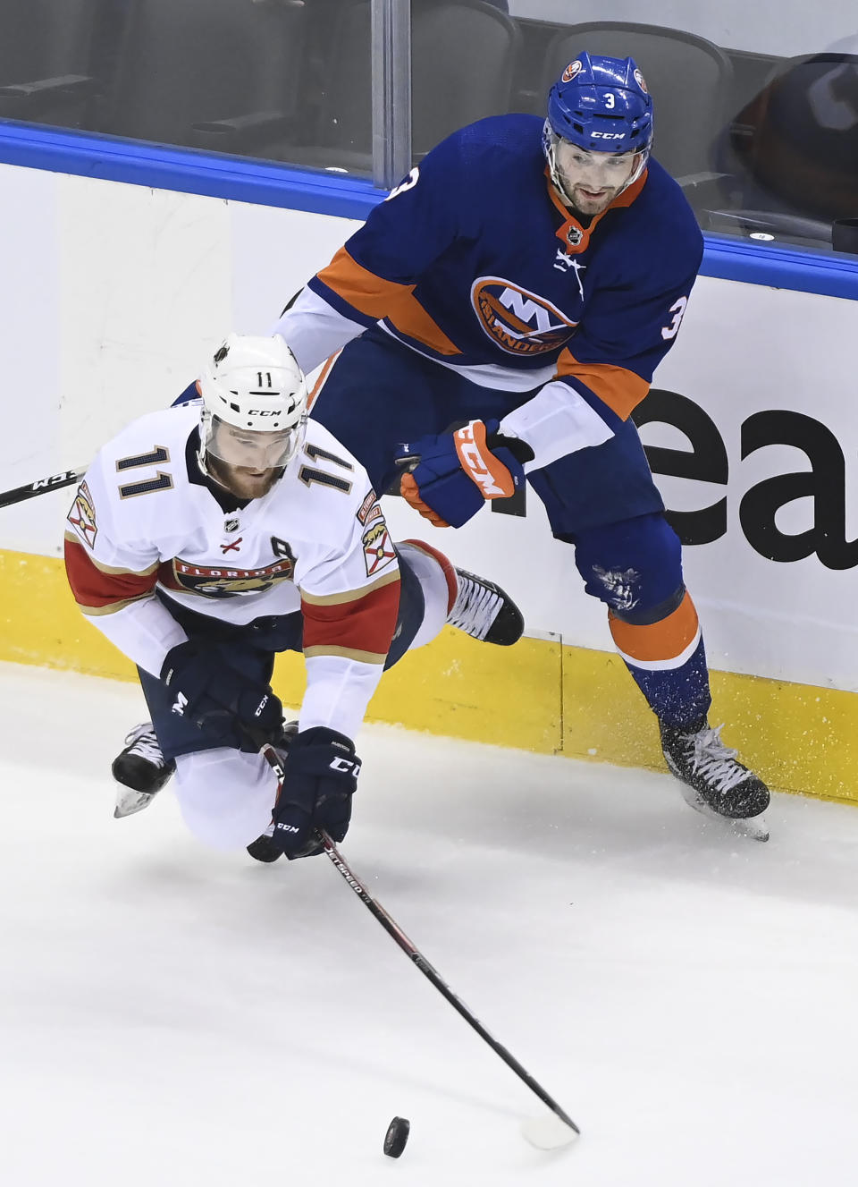 New York Islanders defenseman Adam Pelech (3) trips up Florida Panthers left wing Jonathan Huberdeau (11) during the second period of an NHL Stanley Cup playoff hockey game in Toronto, Tuesday, Aug. 4, 2020. (Nathan Denette/The Canadian Press via AP)