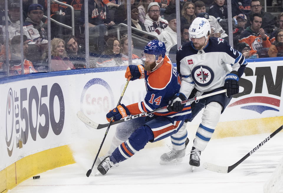 Winnipeg Jets' Blake Wheeler (26) and Edmonton Oilers' Mattias Ekholm (14) vie for the puck during the first period of an NHL hockey game Friday, March 3, 2023, in Edmonton, Alberta. (Jason Franson/The Canadian Press via AP)