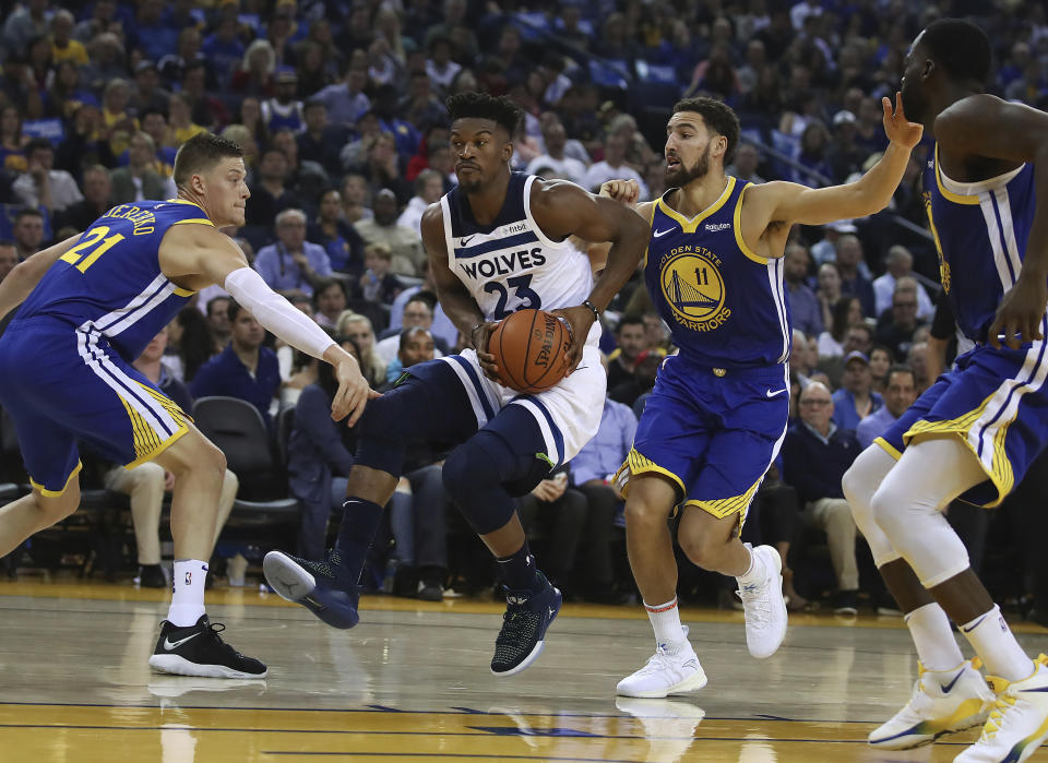 Minnesota Timberwolves' Jimmy Butler (23) drives the ball between Golden State Warriors' Jonas Jerebko, left, and Klay Thompson (11) during the first half of an NBA basketball game Friday, Nov. 2, 2018, in Oakland, Calif. (AP Photo/Ben Margot)