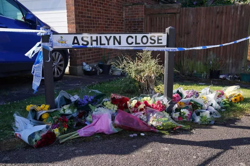 Bouquets of flowers underneath a street sign saying Ashlyn Close