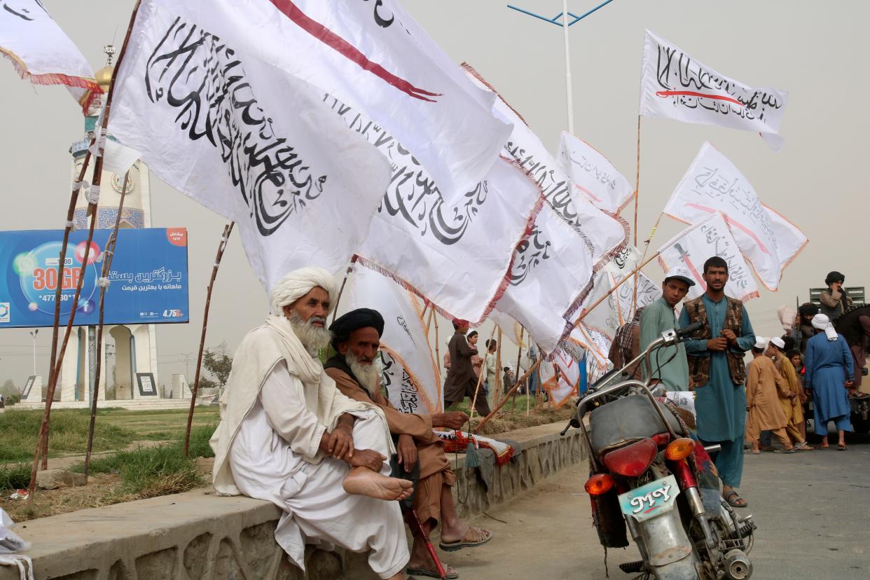 Elderly Afghan men sit near the Taliban flags during a celebration marking the second anniversary of the withdrawal of U.S.-led troops from Afghanistan, in Kandahar, south of Kabul, Afghanistan on Aug. 15.