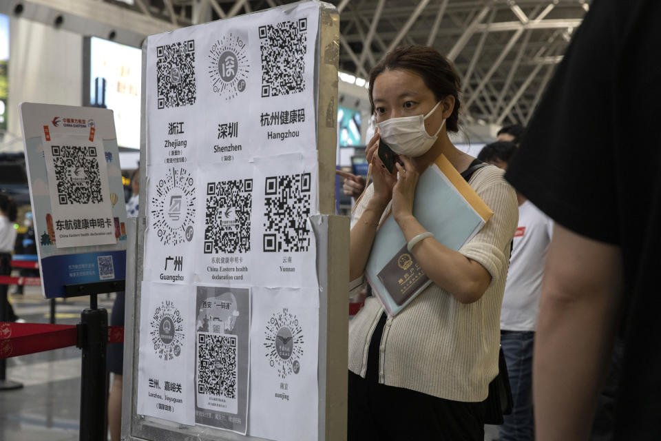 A passenger looks at a board with QR codes for health screening from different provinces at the Beijing Capital Airport terminal 2 in Beijing on Wednesday, June 17, 2020. The Chinese capital on Wednesday canceled more than 60% of commercial flights and raised the alert level amid a new coronavirus outbreak, state-run media reported. (AP Photo/Ng Han Guan)