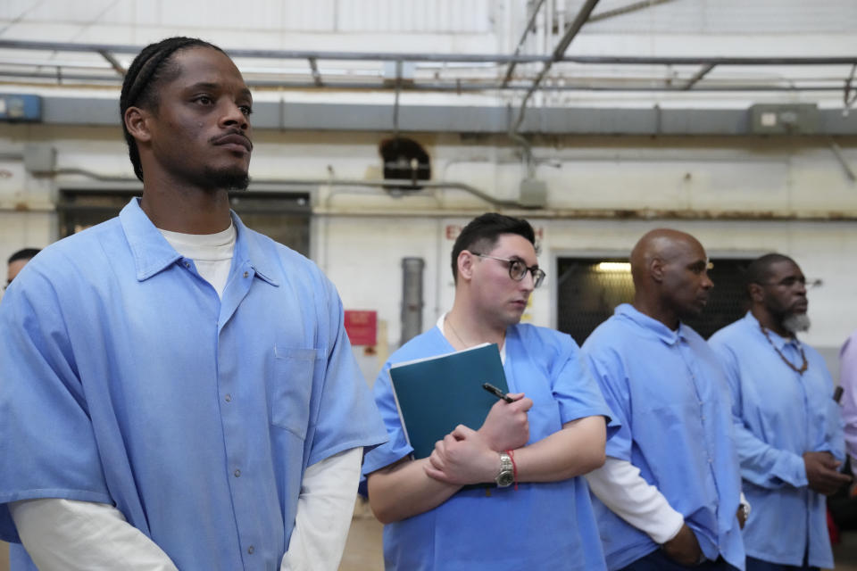 Incarcerated men Deandre Brumfield, left, and Tony Tafoya, second from left, listen as California Gov. Gavin Newsom speaks inside a warehouse at San Quentin State Prison in San Quentin, Calif., Friday, March 17, 2023. Newsom plans to transform the prison, a facility in the San Francisco Bay Area known for maintaining the highest number of prisoners on death row in the country. Newsom said his goal is to turn the prison into a place where inmates can be rehabilitated and receive job training before returning to society. (AP Photo/Eric Risberg)
