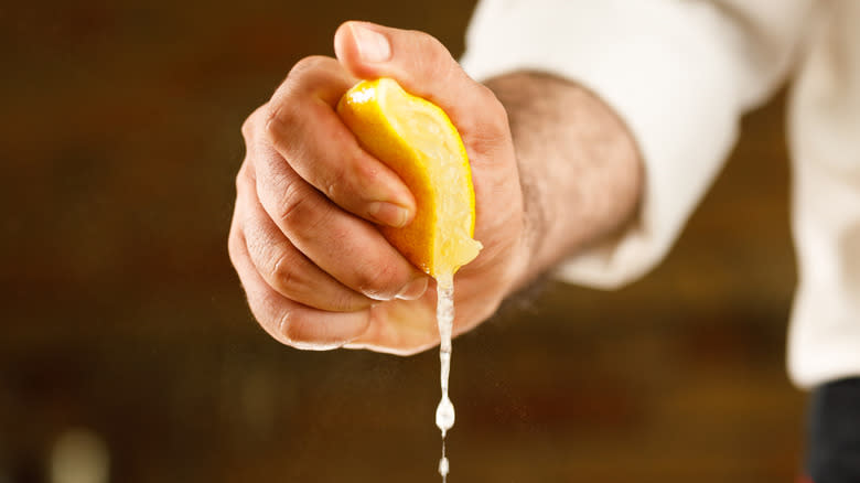 a man's hand squeezing lemon