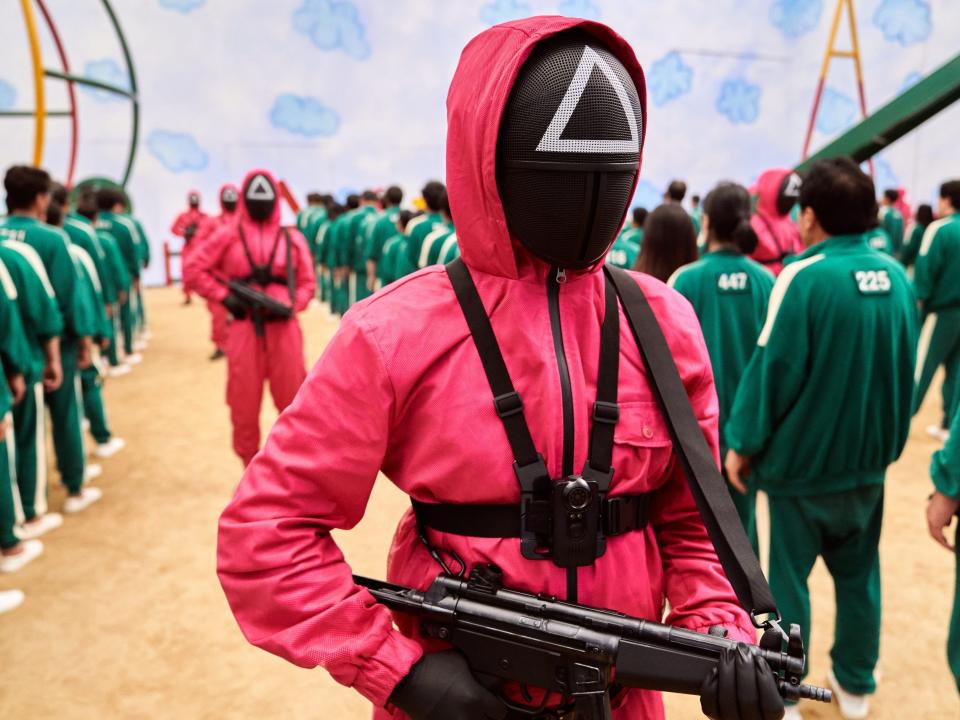 A triangle pink jacket with a gun in "Squid Game"