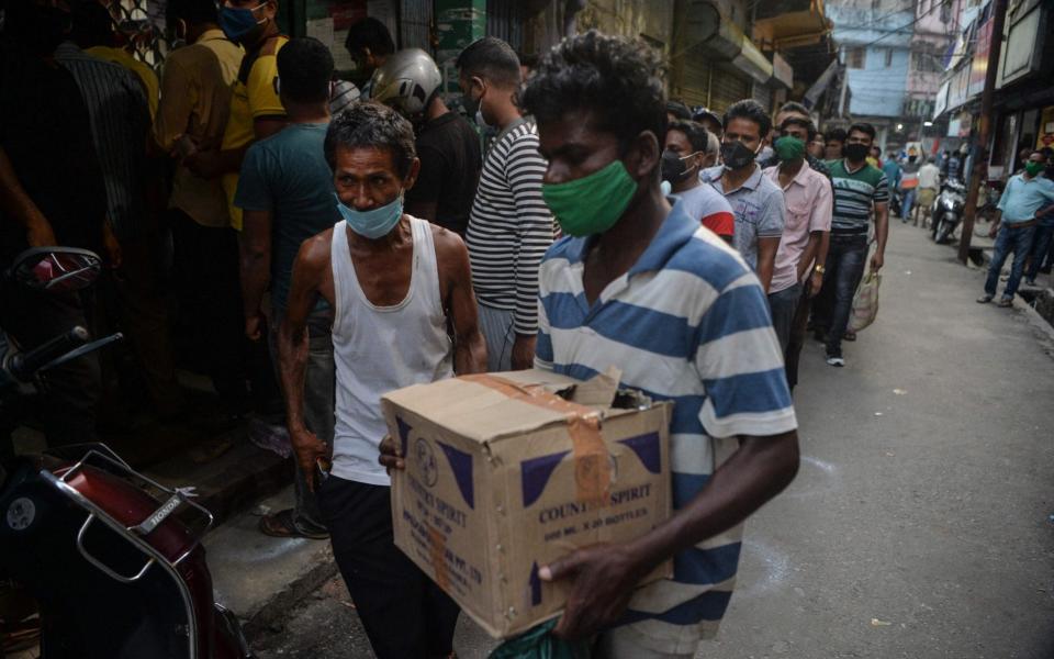 People queue to buy alcohol after West Bengal's government announced a 15-day partial lockdown and travel restrictions including amid the Covid-19 coronavirus pandemic, in Siliguri - DIPTENDU DUTTA / AFP