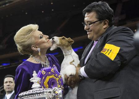 AfterAll Painting the Sky, a wire fox terrier, is held by her handler Gabriel Rangel (R) as she kisses judge Betty Regina Leininger (L) after winning "best in show" at the 2014 Westminster Kennel Club Dog Show in New York February 11, 2014. REUTERS/Keith Bedford