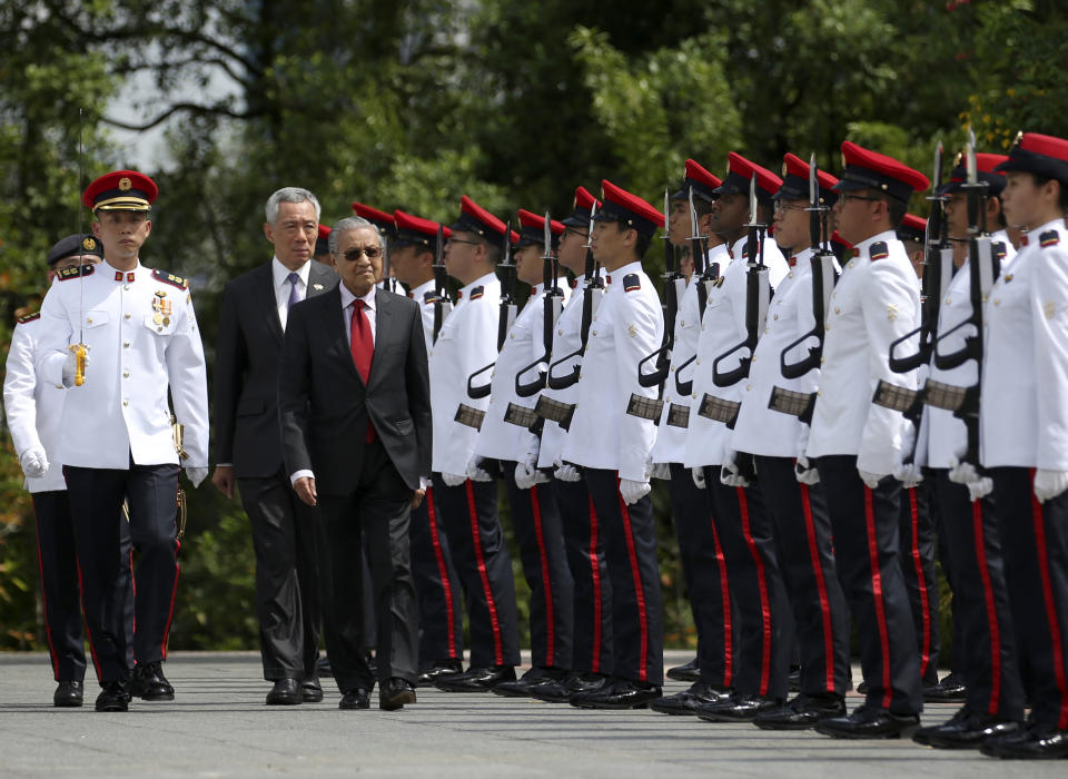 Malaysia's Prime Minister Mahathir Mohamad, center, inspects an honor guard with Singapore's Prime Minister Lee Hsien Loong, center left, during a visit at the Istana in Singapore, Monday, Nov. 12, 2018. (Feline Lim/Pool Photo via AP)