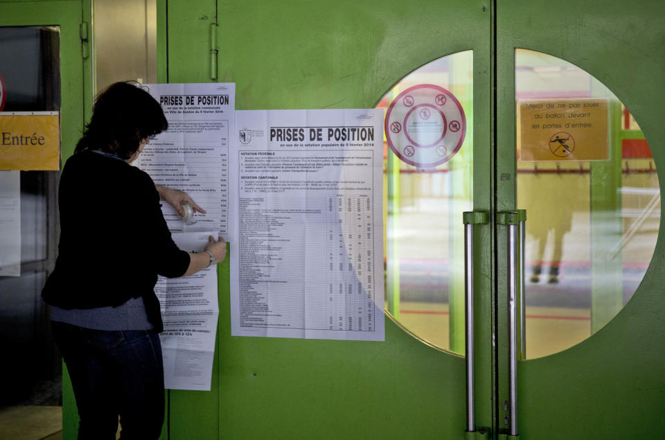An electoral worker places the voting guidelines outside a polling station before Swiss voters went to the polls to decide on a proposal to cap immigration to the Alpine republic, in the center of Geneva, Switzerland, Sunday, Feb. 9, 2014. The nationalist Swiss People’s Party demands a stop for immigration to Switzerland. (AP Photo/Anja Niedringhaus)