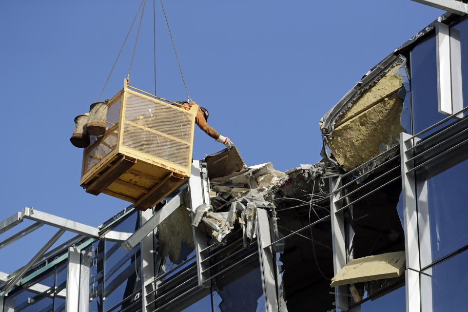 A worker suspended in a basket reaches out toward debris from a building damaged when the crane atop it collapsed a day earlier, Sunday, April 28, 2019, in Seattle. The construction crane fell from a building on Google's new campus during a storm that brought wind gusts, crashing down onto one of the city's busiest streets and killing multiple people. (AP Photo/Elaine Thompson)