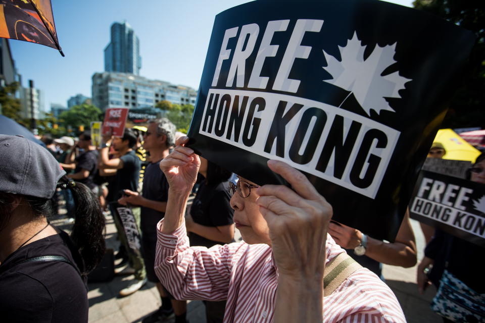 An elderly woman holds a sign while listening to speakers during a rally in support of Hong Kong anti-extradition bill protesters, in Vancouver, Saturday, Aug. 3, 2019. The demonstration was one of many held in cities across Canada Saturday. THE CANADIAN PRESS/Darryl Dyck