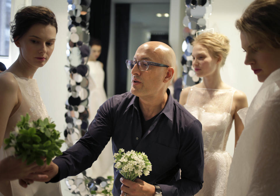 Designer Angel Sanchez helps to prepare models backstage before his 2013 bridal show in New York, Monday, April 22, 2013. (AP Photo/Seth Wenig)