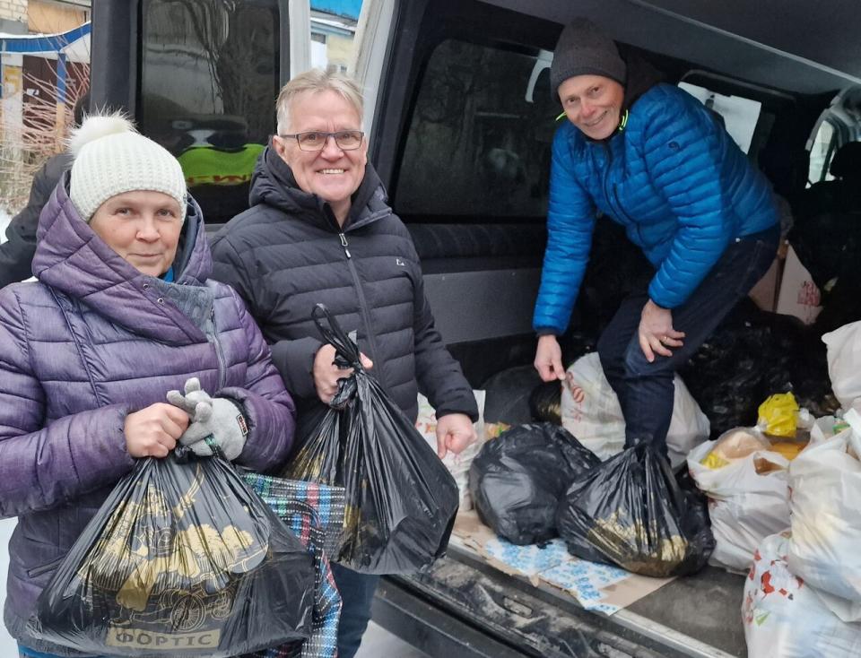 Ed Dickson, in black jacket, and Cory Jones' father Bob Jones, in blue jaacket, handing out groceries to Ukrainians who lived along the front line in 2023.