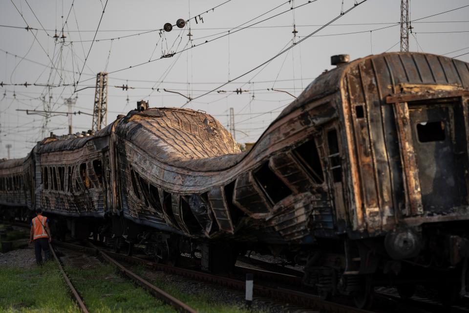 A railway worker stands next to heavily damaged train after a Russian attack on a train station yesterday during Ukraine's Independence Day in the village Chaplyne, Ukraine, Thursday, Aug. 25, 2022.