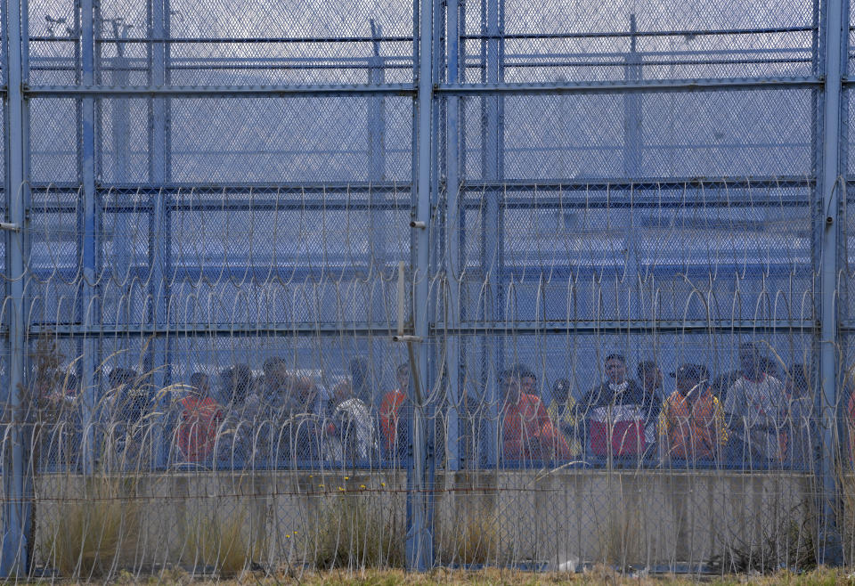 Inmates are held at a prison yard after a deadly riot in Latacunga, Ecuador, Tuesday, Oct. 4, 2022. A clash between inmates armed with guns and knives inside the prison has left at least 15 people dead and 20 injured. (AP Photo/Dolores Ochoa)