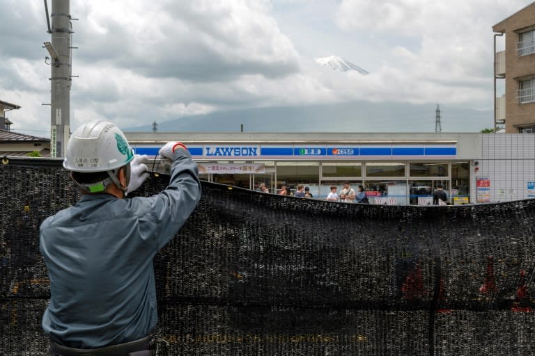 Un operador municipal instala una malla negra para tapar una popular vista al monte Fuji en el pueblo japonés de Fujikawaguchiko (Kazuhiro NOGI)