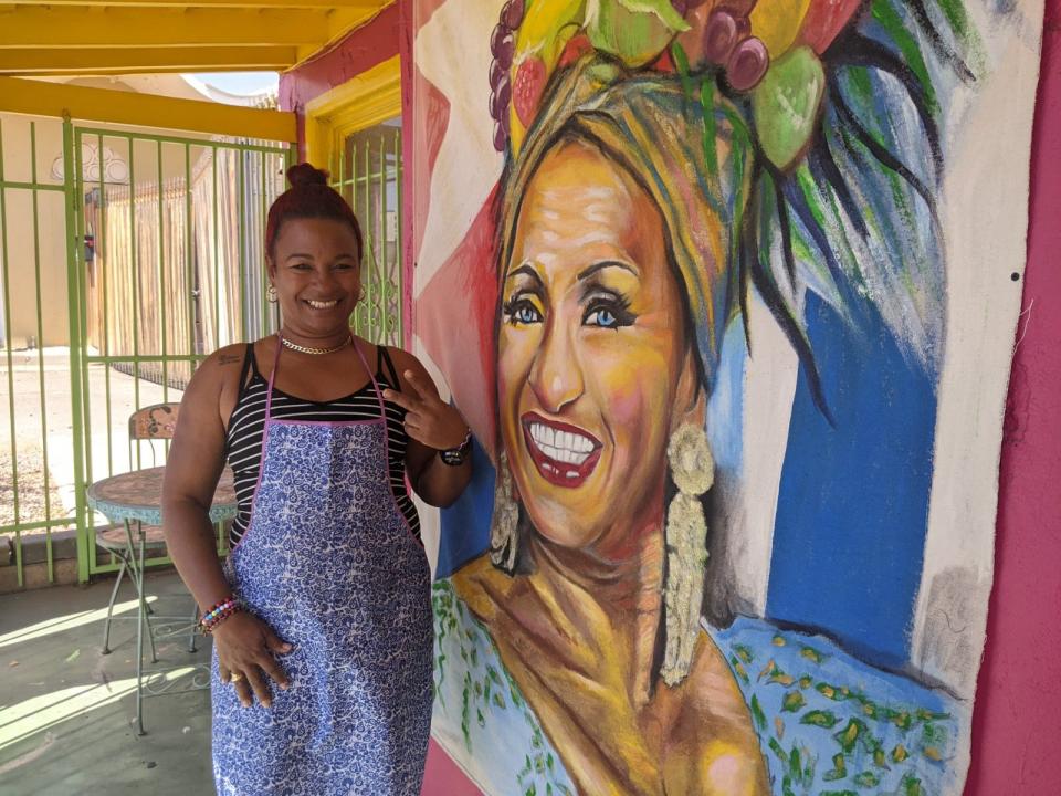 Arianna Pared Villegas poses next to a painting of singer Celia Cruz that hangs outside her Phoenix restaurant, Cocina La Negra, on May 7, 2022.