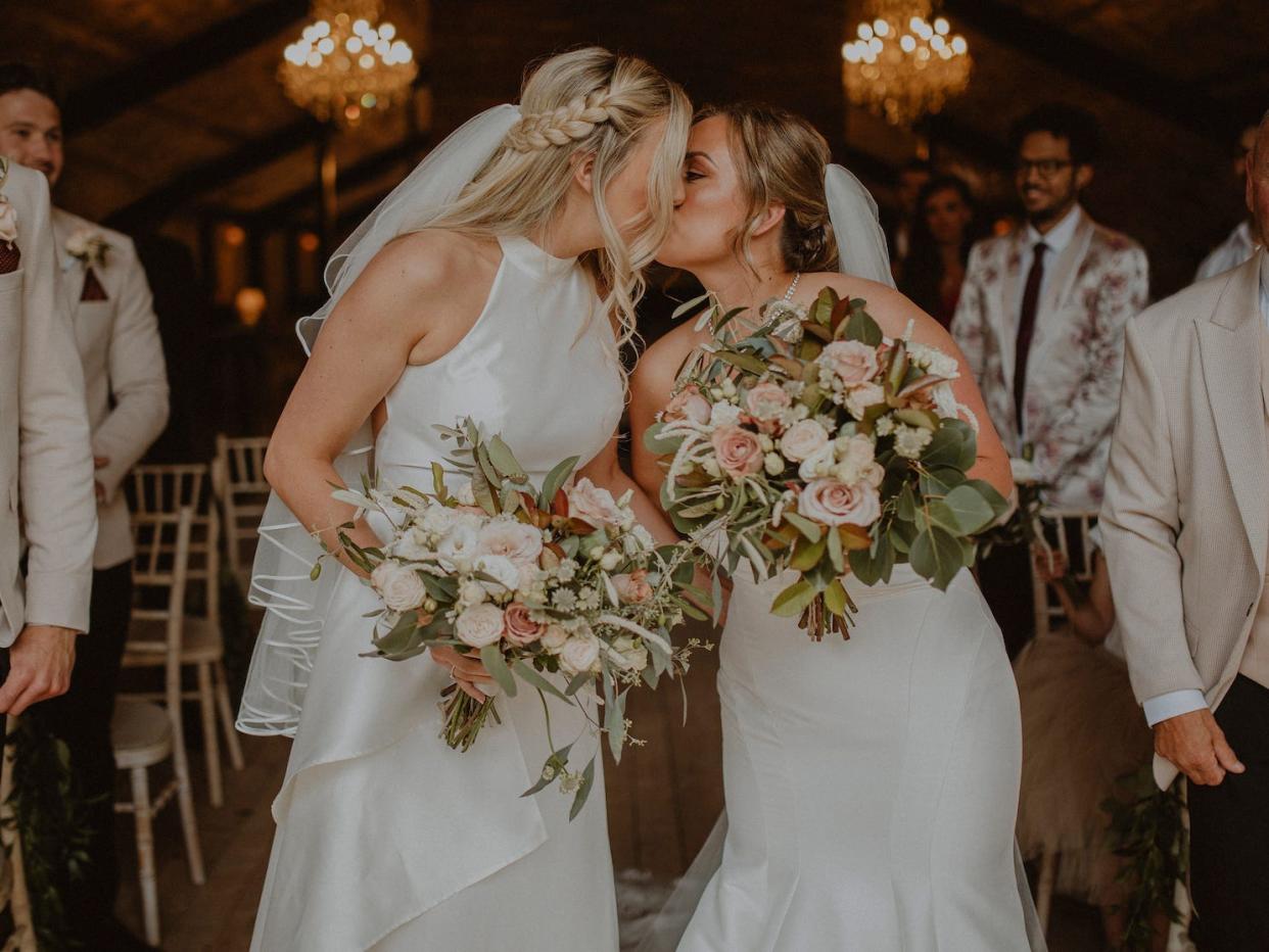 Two brides kiss as they exit their wedding ceremony.