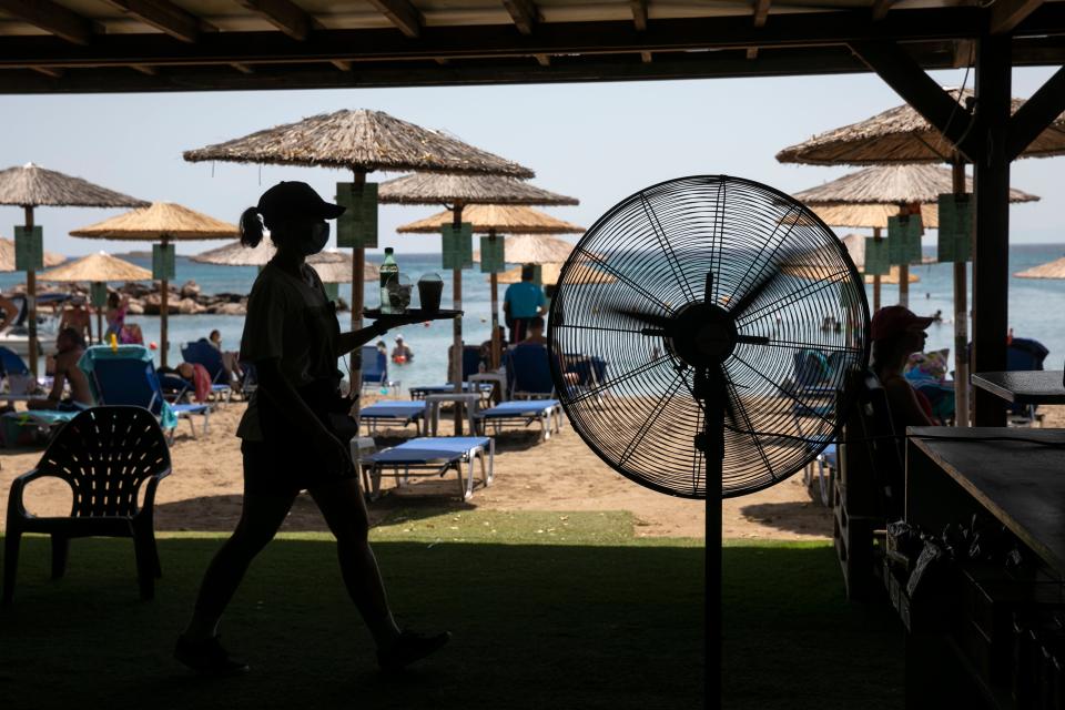 A waitress serves refreshments at a beach bar of Lagonissi village, a few miles southwest of Athens, on Thursday (AP)