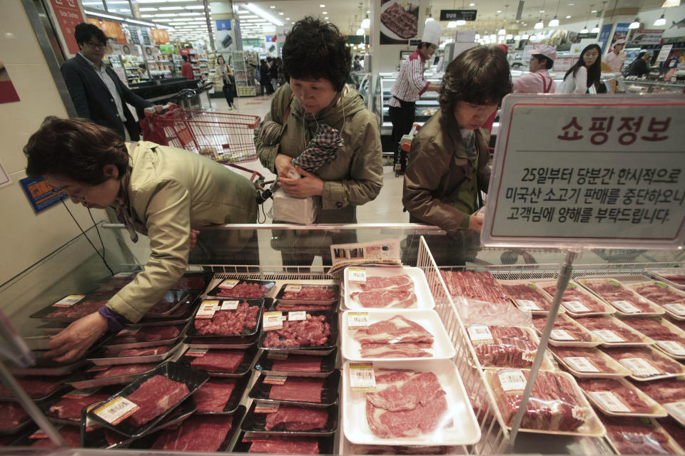 South Korean shoppers watch to buy domestic and Australian beef on the shelves at a Lotte Mart store in Seoul, South Korea, Wednesday, April 25, 2012. Two major South Korean retailers, including Lotte Mart, suspended sales of U.S. beef Wednesday following the discovery of mad cow disease in a U.S. dairy cow. Reaction elsewhere in Asia was muted with Japan saying there's no reason to restrict imports. The letters on a card read " Starting from the 25th, we will temporarily stop the sales of the US beef. Thank you for your understanding". (AP Photo/Ahn Young-joon)