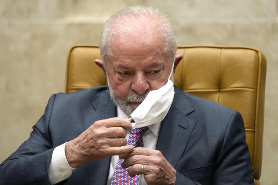 Brazil's President Luiz Inacio Lula da Silva removes his mask, following medical directives to avoid the possibility of contracting a respiratory illness before his scheduled operation, during a ceremony in the Supreme Court in Brasilia, Brazil, Thursday, Sept. 28, 2023. Lula is expected to undergo hip replacement surgery tomorrow morning at the Sirio-Libanes hospital in Brasilia. (AP Photo/Eraldo Peres)