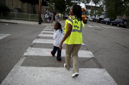 Safe Passage worker Irene Fonder helps a Sherwood Elementary School student cross an intersection in the Englewood neighborhood in Chicago, Illinois, United States, September 8, 2015. REUTERS/Jim Young
