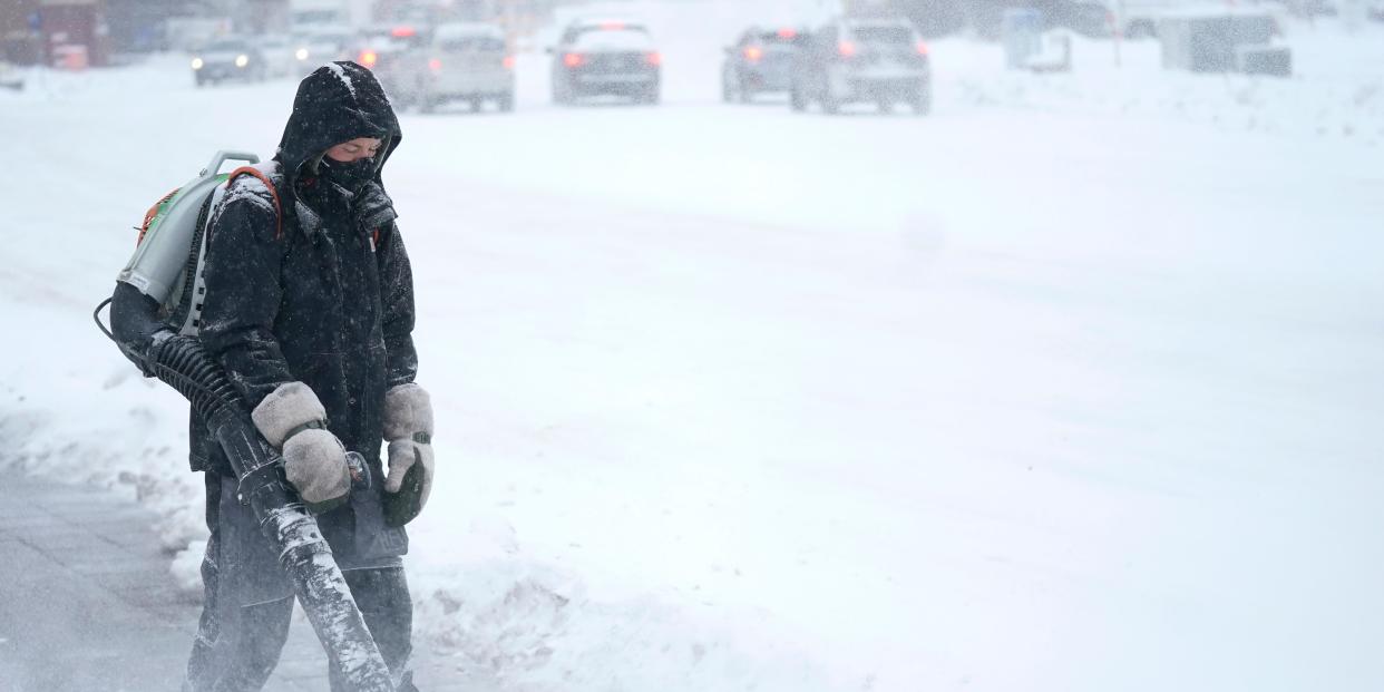 A man blows snow off a sidewalk Wednesday, Dec. 21, 2022, in Minneapolis.