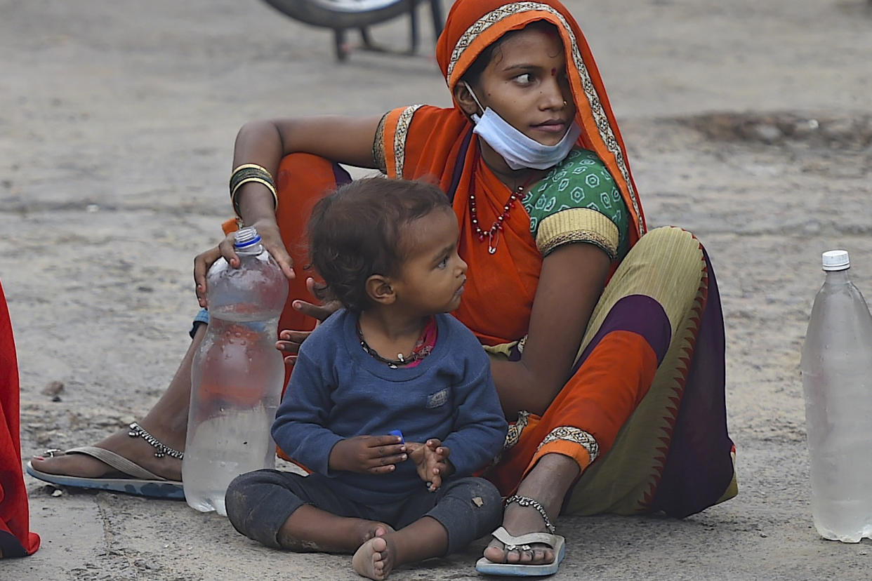 A migrant worker with her child sits on a roadside as she takes a break on her journey towards their respective hometown state during a government-imposed nationwide lockdown as a preventive measure against the COVID-19 coronavirus, in Faridabad on May 13, 2020. (Photo by Money SHARMA / AFP) (Photo by MONEY SHARMA/AFP via Getty Images)