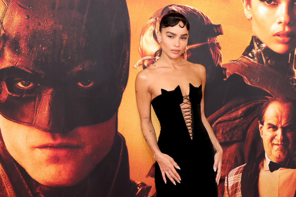 Zoe standing in front of a backdrop featuring a photo of Batman, herself as Catwoman and the Penguin