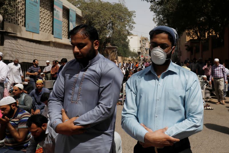A man wears a protective mask as a preventive measure amid coronavirus fears, as he attends Friday prayers with others in Karachi
