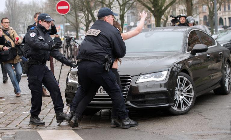 French police detain a topless Femen activist who jumped on the car carrying ex-IMF chief Dominique Strauss-Kahn (not seen) to the courthouse for his trial in Lille, on February 10, 2015