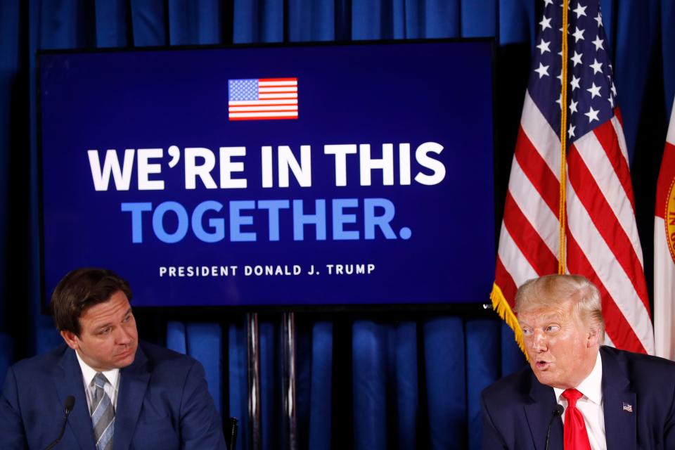 Gov. Ron DeSantis (left) listens as President Donald Trump speaks during a roundtable discussion on the coronavirus in 2020.