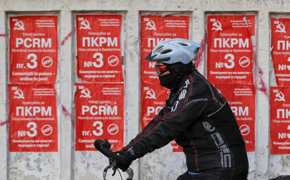 A man rides a bicycle by electoral posters advertising the Communist party in Chisinau, Moldova, Thursday, Feb. 21, 2019, ahead of parliamentary elections taking place on Feb. 24. Moldova's president says the former Soviet republic needs good relations with Russia, amid uncertainty about the future of the European Union. (AP Photo/Vadim Ghirda)