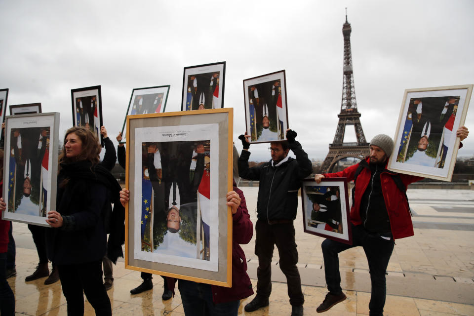 A hundred activists hold portraits of President Emmanuel Macron to urge France to take action during the U.N. COP 25 climate talks in Madrid, during a gathering at Place du Trocadero facing the Eiffel Tower in Paris, Sunday, Dec. 8, 2019. Environmental activists around France have removed President Emmanuel Macron's official portrait from town halls around the country in an unusual protest movement aimed at pushing him to do more to slow climate change. (AP Photo/Francois Mori)