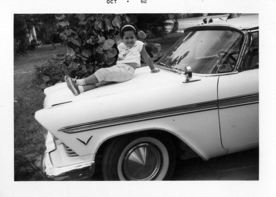 Flashback: Young Liz Balmaseda smiles from atop the family car in 1962 Miami.