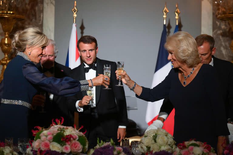 La esposa del presidente francés, Brigitte Macron, y la reina británica, Camilla, brindan junto al rey Carlos III y el presidente francés, Emmanuel Macron, durante un banquete de Estado en el Palacio de Versalles. (Daniel LEAL / POOL / AFP)