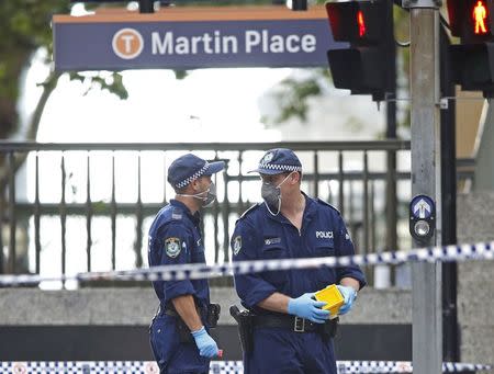 New South Wales police officers wear protective masks as they place marker cones over potential evidence in their investigation into the Sydney cafe siege, December 16, 2014. REUTERS/Jason Reed