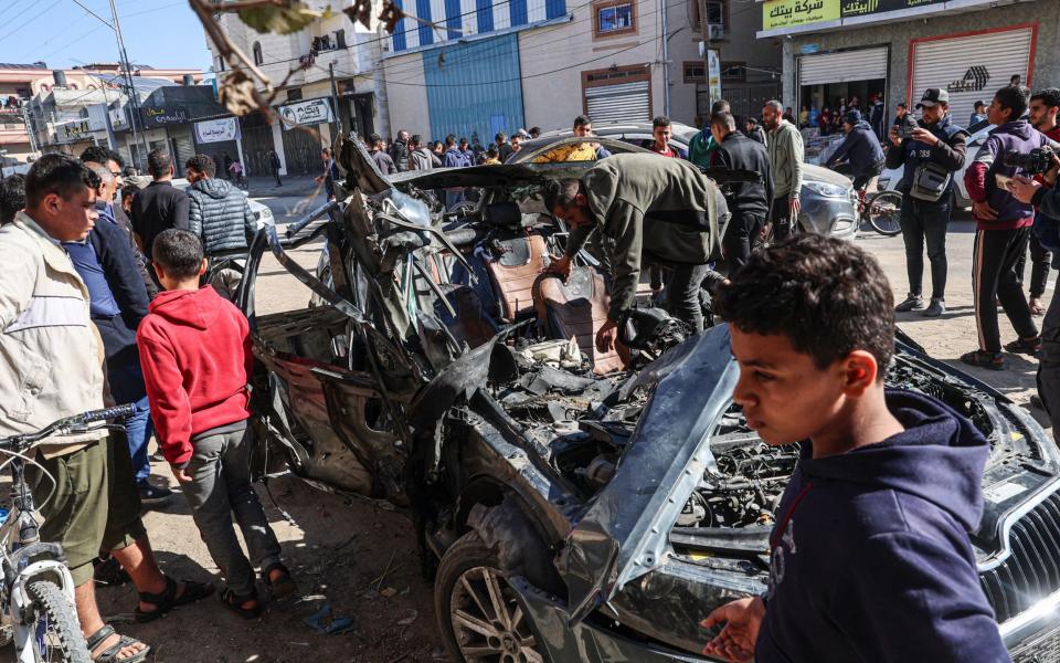 People check the car in which two journalists,Mustafa Thuria, a video stringer for AFP news agency, and Hamza Wael Dahdouh, a journalist with Al Jazeera television network, were killed