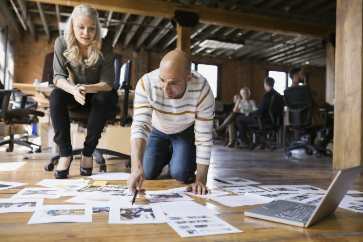 Business people look at proofs on the floor. (Getty Stock)