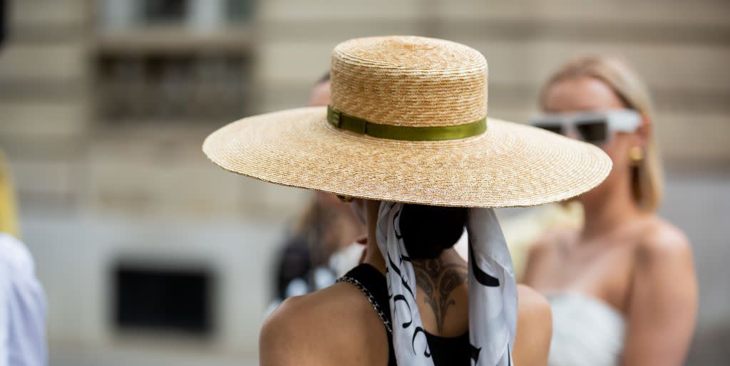a guest at paris fashion week wears a straw hat tied with a scarf to illustrate a guide to the best straw hats of 2023