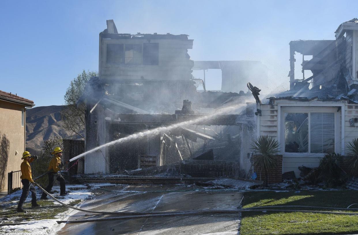 Firefighters hose down a burning house during the Tick Fire in Agua Dulce near Santa Clarita, Calif. on Oct. 25, 2019.