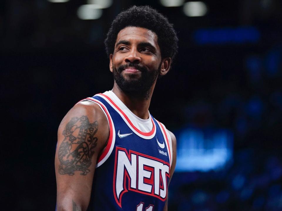 Kyrie Irving looks to his right and smiles during a Nets game in 2022.