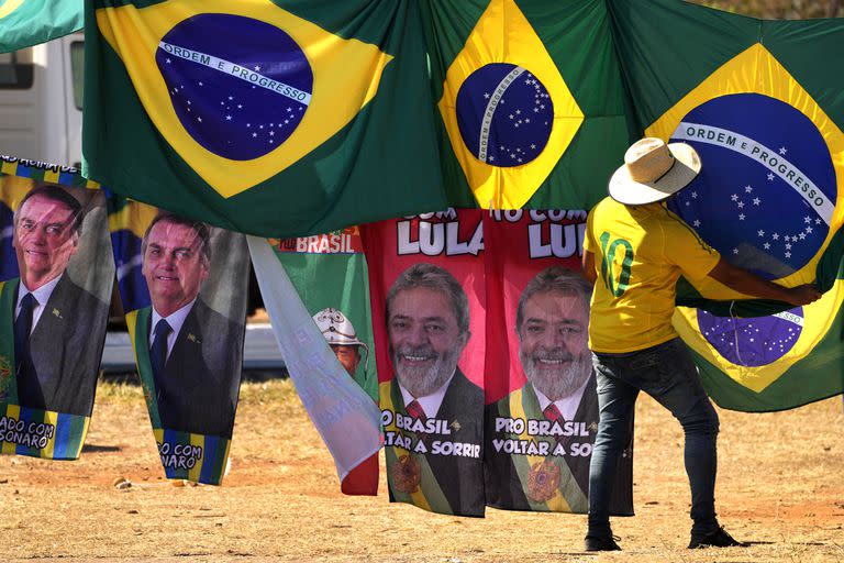 Retratos del presidente Jair Bolsonaro, a la izquierda, y del exmandatario Luiz Inácio Lula da Silva, al centro, cuelgan en el exterior de al Corte Suprema Electoral en Brasilia, abajo de banderas brasileñas, el 5 de septiembre de 2022. 