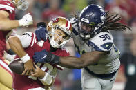 FILE - In this Nov. 11, 2019, file photo, San Francisco 49ers quarterback Jimmy Garoppolo, left, avoids being sacked by Seattle Seahawks defensive end Jadeveon Clowney (90) during the second half of an NFL football game in Santa Clara, Calif. Even with the status of the upcoming season uncertain because of the coronavirus pandemic, teams continue to tinker with their rosters by adding players they hope will help them win — whenever, or if, they actually play. Many believed Clowney would be snatched up by a team desperate for a pass-rushing presence during the first few days of free agency. And, for big-time bucks. Instead, the 2014 No. 1 overall pick is still unsigned two months later and potentially looking at a one-year, prove-it deal. A return to Seattle isn't out of the question. (AP Photo/Tony Avelar, File)
