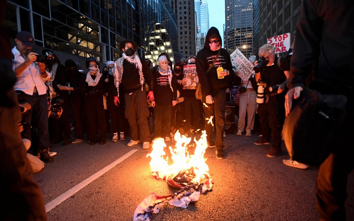 Pro-Palestine demonstrators burn a US-Israel flag during a protest as the Democratic National Convention takes place in Chicago