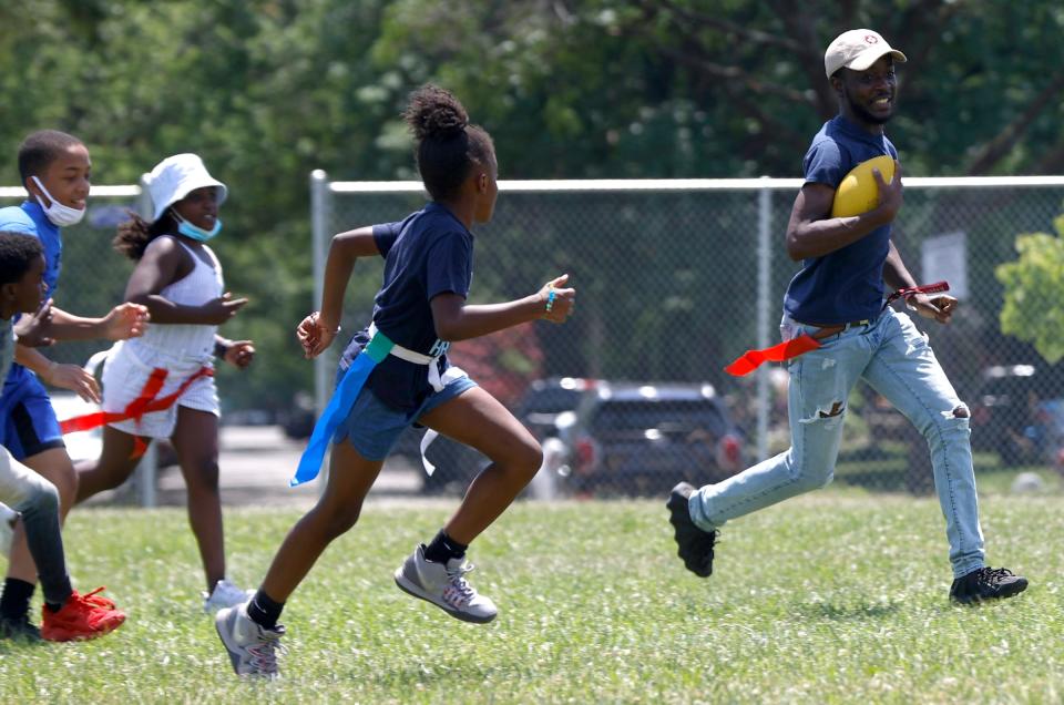 Isaiah Pelt, 24, of Detroit, is a camp counselor at the What's Good In My Hood Outdoor Adventure Camp and runs past campers playing flag football at the Tindal Recreation Center in Detroit on Thursday, June 30, 2022.