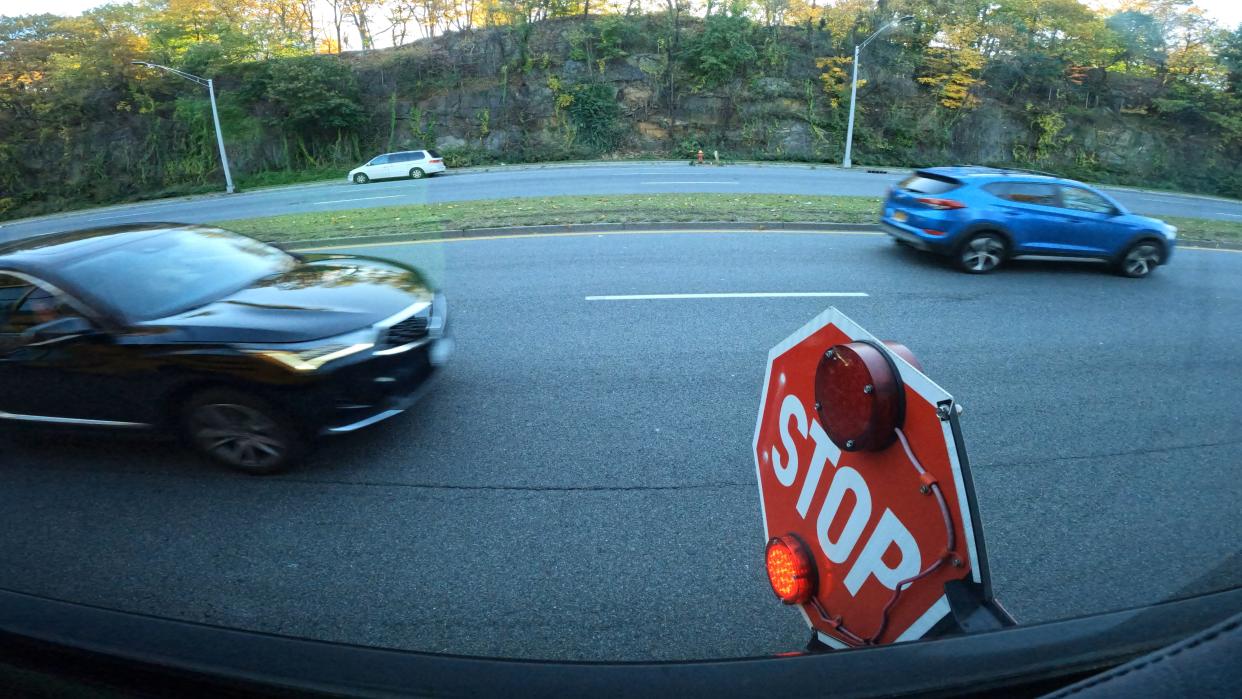 Two cars drive past a school bus' flashing stop sign on Central Park Ave. in Yonkers. The First Student bus was taking students to the Casimir Pulaski School Weds. morning Nov. 8, 2023.
