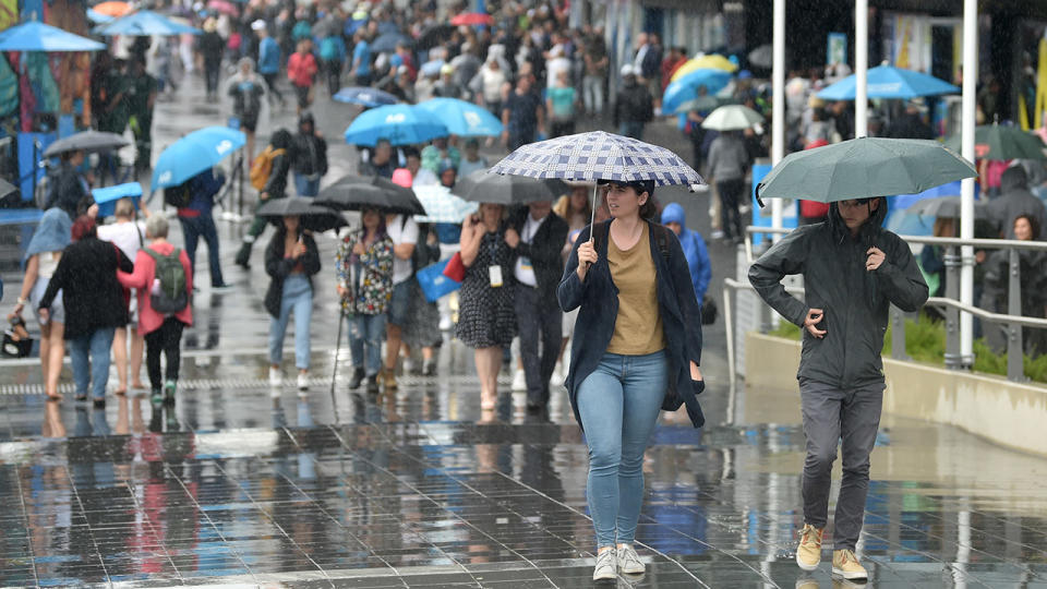 Australian Open spectators, pictured here taking cover as rain falls on day one.