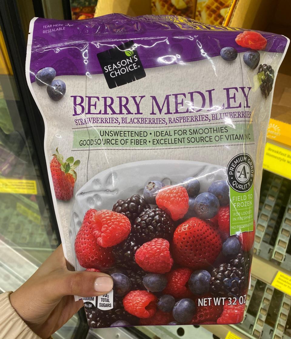 Hand holding a pack of frozen berry medley at Aldi